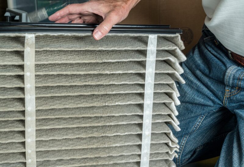 technician switching out a dirty air filter from the furnace in a carlsbad home